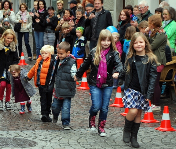 Kinder in gewöhnlicher Straßenkleidung - warm angezogen -  gehen durch die feldkircher Innenstadt um ihre modische Kleidung zu präsentieren. 