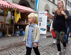 Sowohl eine junge Erwachsene als auch Kinder in Tracht gehen durch die feldkircher Innenstadt um ihre modische Kleidung zu präsentieren. 