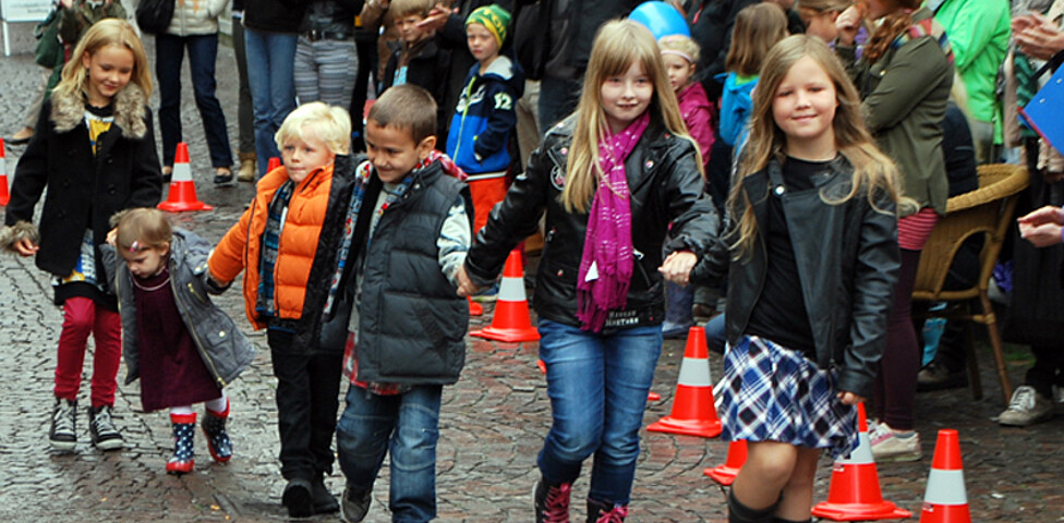 Kinder in gewöhnlicher Straßenkleidung - warm angezogen -  gehen durch die feldkircher Innenstadt um ihre modische Kleidung zu präsentieren. 