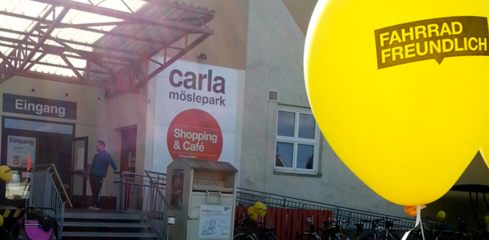 Ein gelber Luftballon befindet sich im Vorder- und im Hintergrund ein großes Betriebsgebäude.