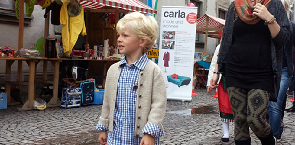 Sowohl eine junge Erwachsene als auch Kinder in Tracht gehen durch die feldkircher Innenstadt um ihre modische Kleidung zu präsentieren. 